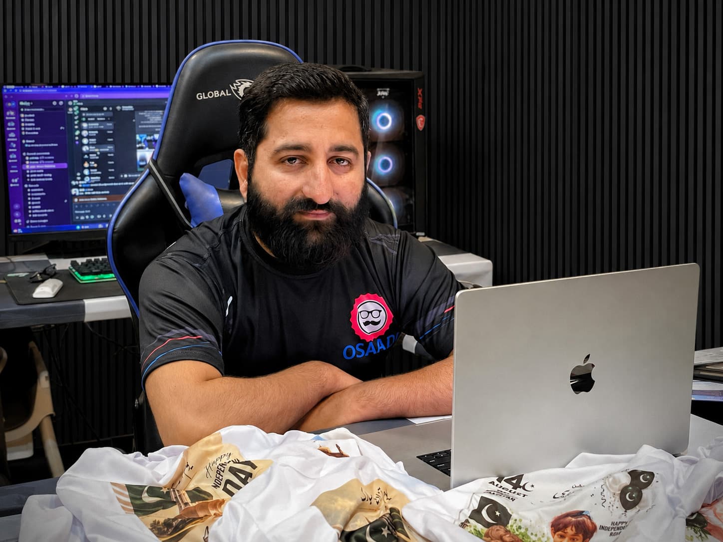 Usama Saad at his desk, with his laptop and printed products in the foreground